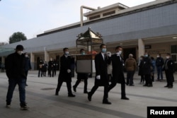 四川成都一个火葬场工作人员抬着一名逝者的骨灰盒走出火葬场。(2022年12月28日)