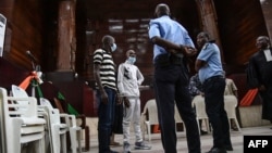 Sidi Mohamed Kounta et Hantao Ag Mohamed Cisse, deux des quatre accusés de l'attaque de Grand Bassam, se tiennent debout après avoir été condamnés à la prison à vie, le 28 décembre 2022. AFP / Sia Kambou
