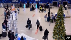 Sejumlah penumpang tampak hilir mudik di area gerbang Terminal C Bandara Internasional Logan di Boston, pada 21 November 2022. (Foto: AP/Charles Krupa) 