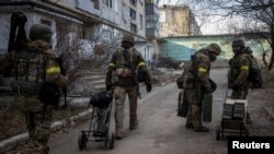 Ukrainian service members carry weapons in Bakhmut in Donetsk region as Russia's attack on Ukraine continues, Dec. 7, 2022.