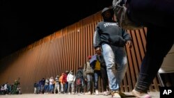 FILE - A group of migrants, mostly from Cuba, line up to board a bus after crossing the border from Mexico and surrendering to authorities to apply for asylum on Nov. 3, 2022, near Yuma, Arizona. 