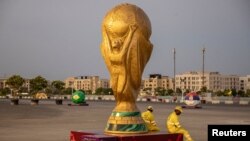Pekerja duduk di samping replika Piala Dunia di luar Stadion Lusail jelang Piala Dunia, di Lusail, Qatar, 10 November 2022 REUTERS/Marko Djurica