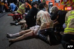 Emergency workers and others assist people who were caught in a Halloween stampede in the district of Itaewon in Seoul, South Korea, Oct. 29, 2022. More than 150 people have been killed in the stampede.