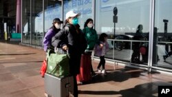 In this file photo, passengers are seen wearing masks as they walk through the Capital airport terminal in Beijing on Dec. 13, 2022. (AP Photo/Ng Han Guan, File)