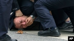 FILE - Policemen pin down and detain a protester during a protest on a street in Shanghai, China on Nov. 27, 2022. (AP Photo, File)