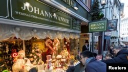 Orang-orang melihat melalui jendela toko Weihnachtshaus (Rumah Natal) Johann Wanner, produsen hiasan Natal buatan tangan terbesar di dunia, di Basel, Swiss, 6 Desember 2022. (REUTERS/Denis Balibouse)