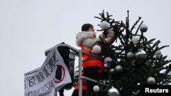 Para aktivis "Letzte Generation" (Generasi Terakhir) memotong pucuk pohon Natal di Gerbang Brandenburg, di Berlin, Jerman, 21 Desember 2022. (REUTERS/Christian Mang)