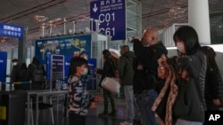FILE - Passengers wearing face masks line up for a security check to enter a departure gate at Beijing Capital International Airport, in Beijing, China, Dec. 29, 2022.