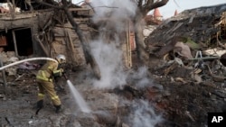 Firefighters extinguish a fire next to houses destroyed during a Russian attack in Kyiv, Ukraine, Dec. 31, 2022.