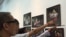 Visitors point to photos of Em Theay, now 85, taken by photographer Aray Steven, on display at National Museum in Phnom Penh, November 1, 2015. (Photo: Phorn Bopha/VOA Khmer) 