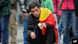 Un citoyen belge pose mercredi une bougie sur la Place de la Bourse au centre de Bruxelles en mémoire des victimes des attentats terroristes du 23 mars 2016. 