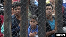 Members of a migrant caravan from Central America and their supporters look through the U.S.-Mexico border wall at Border Field State Park before making an asylum request, in San Diego, California, U.S. April 29, 2018. REUTERS/Lucy Nicholson