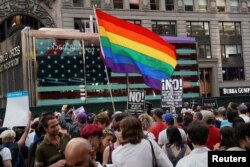 A rainbow flag flies as people protest U.S. President Donald Trump's announcement that he plans to reinstate a ban on transgender individuals from serving in any capacity in the U.S. military, in Times Square, in New York City, New York, July 26, 2017.