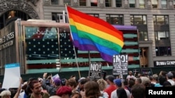 Sebuah bendera pelangi berkibar saat aksi protes terhadap rencana Presiden AS Donald Trump untuk menerapkan kembali larangan bagi kaum transgender untuk melayani dalam kapasitas apapun di militer A.S., di Times Square, di New York City, 26 Juli 2017
