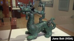 This instrument stand in the form of a "divine beast" combines a dragon's head, tortoise legs, and a tiger's body that's inlaid with phoenix birds.