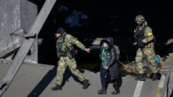 Yon manm fos Ikrenyen yo ede yon dam travese rivye Irpin nan pandan evakyasyon vil Irpin, bo kote yon pon ki detwi pandan envazyon La Risi fe nan Ikren, Dimanch 13 Mas, 2022. 