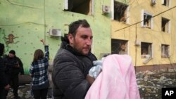 Seorang pria tampak membawa bayi dalam proses evakuasi daru rumah sakit bersalin di Mariupol, Ukraina, pada 9 Maret 2022. Rumah sakit tersebut hancur dalam sebuah serangan yang dilakukan pasukan Rusia. (Foto: AP/Evgeniy Maloletka)