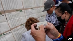 People check a voter list to confirm where they should cast their ballots during legislative elections in Bogota, Colombia, Sunday, March 13, 2022. (AP Photo/Fernando Vergara)