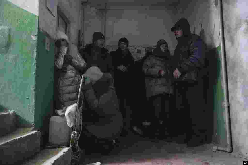 People cover from shelling inside an entryway to an apartment building in Mariupol, Ukraine, March 13, 2022.