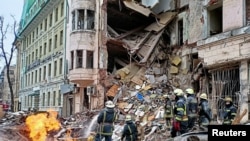 Rescuers work next to a building damaged by air strike, as Russia's attack on Ukraine continues, in central Kharkiv, Ukraine, March 14, 2022.