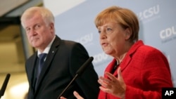 FILE - German Chancellor Angela Merkel, right, and the Governor of the German State of Bavaria, Horst Seehofer, left, address the media during a statement about their talks on the migrant influx in Berlin, Germany, Nov. 3, 2015. 