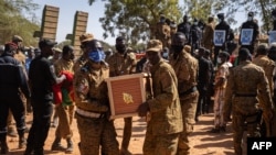 Des militaires burkinabè portent un cercueil d'un soldat dans la section militaire du cimetière de Gounghin à Ouagadougou le 23 novembre 2021, après la mort dudit soldat lors de l'attaque d'un camp de gendarmerie à Inata au Burkina Faso.