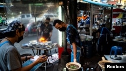 People wearing face masks as protection against the coronavirus disease (COVID-19) sell street food in Bangkok's Chinatown, Thailand, March 17, 2022.