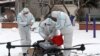 Pekerja dengan pakaian pelindung (APD) menyiapkan drone di tengah salju untuk mendisinfeksi kompleks perumahan yang "lockdown", menyusul meningkatnya kasus COVID-19 di Changchun, provinsi Jilin, China, 14 Maret 2022. (China Daily via Reuters)