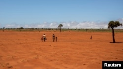 Tarira and her son Avoraza, 4, walk through a field covered with red sand in Anjeky Beanatara, Androy area, Madagascar, February 11, 2022. (REUTERS/Alkis Konstantinidis )