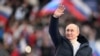 Presiden Rusia Vladimir Putin melambai saat konser menandai ulang tahun kedelapan pencaplokan Krimea oleh Rusia di Stadion Luzhniki di Moskow, Rusia, 18 Maret 2022. (Foto: Sputnik/Ramil Sitdikov/Kremlin via REUTERS)