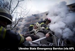14일 러시아군이 우크라이나 수도 크이우(러시아명 키예프) 시내 아파트를 폭격한 직후 소방대원들이 노인을 구출하고 있다.