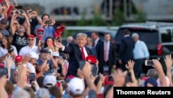 도널드 트럼프(가운데) 전 미국 대통령이 26일 오하이오 집회 참가자들에게 붉은 모자를 던지고 있다.