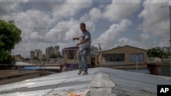 Jorge Ortiz mengikat atap rumahnya untuk bersiap menghadapi Badai Tropis Dorian di kawasan Martín Pena, San Juan, Puerto Rico, 27 Agustus 2019.
