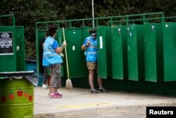 FILE - Workers clean the public lavatories at a farm in Britain, June 22, 2017.