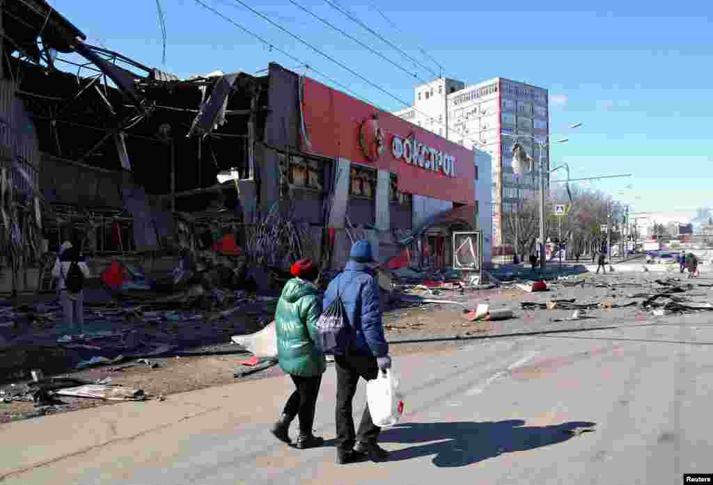 People walk past a Foxtrot store that was destroyed by Russian shelling in Kharkiv, March 15, 2022.
