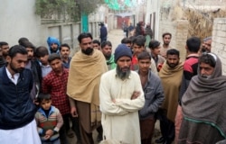 In this Tuesday, Feb. 4, 2020 photo, Pakistani villagers gather outside the home of student Muhimman, who was allegedly abused by a cleric, in Pakpattan, Pakistan. Earlier this year, a cleric at the religious school he faithfully attended raped him…