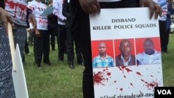 FILE - A protester holds a sign picturing human rights attorney Willie Kimani, his client. Josephat Mwenda. and their taxi driver. Joseph Muiruri. allegedly killed by police, at a rally in Nairobi, Kenya, July 4, 2016. (J. Craig/VOA)