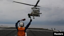 A female flight deck crew of Japanese helicopter carrier Kaga, guides for the landing of a SH-60K Sea Hawk helicopter on the flight deck in the Indian Ocean, Indonesia, Sept. 24, 2018. Japan has increased naval activity in the Southeast Asia in an effort to counterbalance Chinese influence. (REUTERS/Kim Kyung-Hoon)