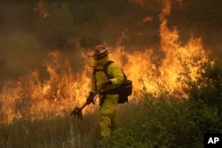 A firefighter with Cal Fire Mendocino Unit walks along a containment line as a wildfire advances, July 30, 2018, in Lakeport, California.