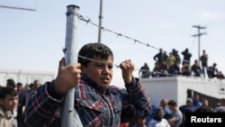 Migrants and refugees look on after minor clashes with Greek policemen occurred at a makeshift camp at the Greek-Macedonian border near the village of Idomeni, Greece, March 29, 2016.