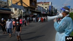 មន្ត្រីយោធាក្នុងឯកសណ្ឋានការពារការឆ្លងមេរោគ កំពុងណែនាំពលរដ្ឋឲ្យតម្រង់ជួរដោយរក្សាគម្លាតពីគ្នា ដើម្បីទទួលការចាក់វ៉ាក់សាំងបង្ការជំងឺកូវីដ១៩ Sinopharm របស់ចិន នៅមណ្ឌលសុខភាពមួយកន្លែងក្នុងរាជធានីភ្នំពេញ កាលពីថ្ងៃទី ៣ ខែឧសភា ឆ្នាំ ២០២១។