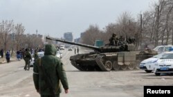 Anggota pasukan pro-tentara Rusia terlihat menaiki tank di Kota Mariupol, Ukraina, pada 20 Maret 2022. (Foto: Reuters/Alexander Ermochenko)