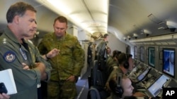 印太美军司令约翰∙阿奎利诺（左）海军上将在美国海军一架飞临南沙群岛上空的P-8A“波塞冬”侦察机上观看中国在人工岛上建造的建筑物的视频。 (2022年3月20日)