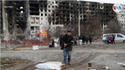 Ljudi ispred uništenih zgrada u Marijupolju, mart 2022.