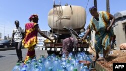 Des Sénégalais recueillent l'eau d'une citerne.
