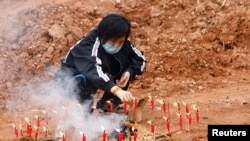 A woman takes part in a Buddhist ceremony in honor of the victims in a field close to the site where a China Eastern Airlines Boeing 737-800 plane crashed, in Wuzhou, Guangxi Zhuang Autonomous Region, China, March 22, 2022. 