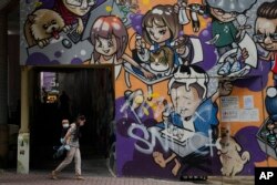 A woman and a child wearing face masks walk along a street in Hong Kong, March 22, 2022.