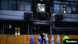 Medical staff in personal protective equipment (PPE) work in front of barriers of an area under lockdown, amid the coronavirus disease (COVID-19) pandemic, in Shanghai, China March 25, 2022.