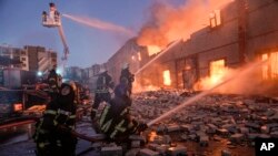Petugas pemadam kebakaran Ukraina memadamkan kobaran api di gudang pasca ledakan bom di Kyiv, Ukraina, Kamis, 17 Maret 2022. (Foto: AP)