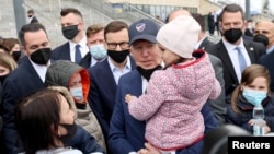 جو بایدن، رئیس جمهوری آمریکا، یک کودک آواره اوکراینی را در آغوش گرفته است. استادیوم ملی پی‌جی‌ای در ورشو، پایتخت لهستان. ۲۶ مارس ٢٠٢٢